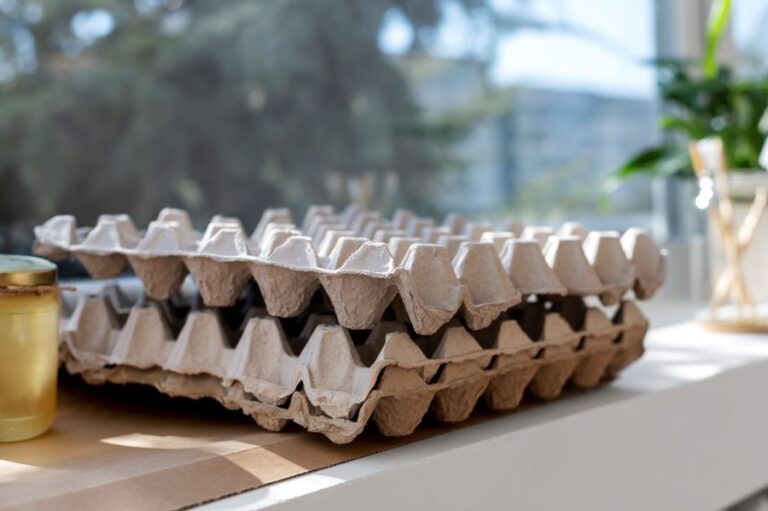 This image shows two stacked pulp egg trays made of recycled paper, resting on a white surface that used for soundproof.